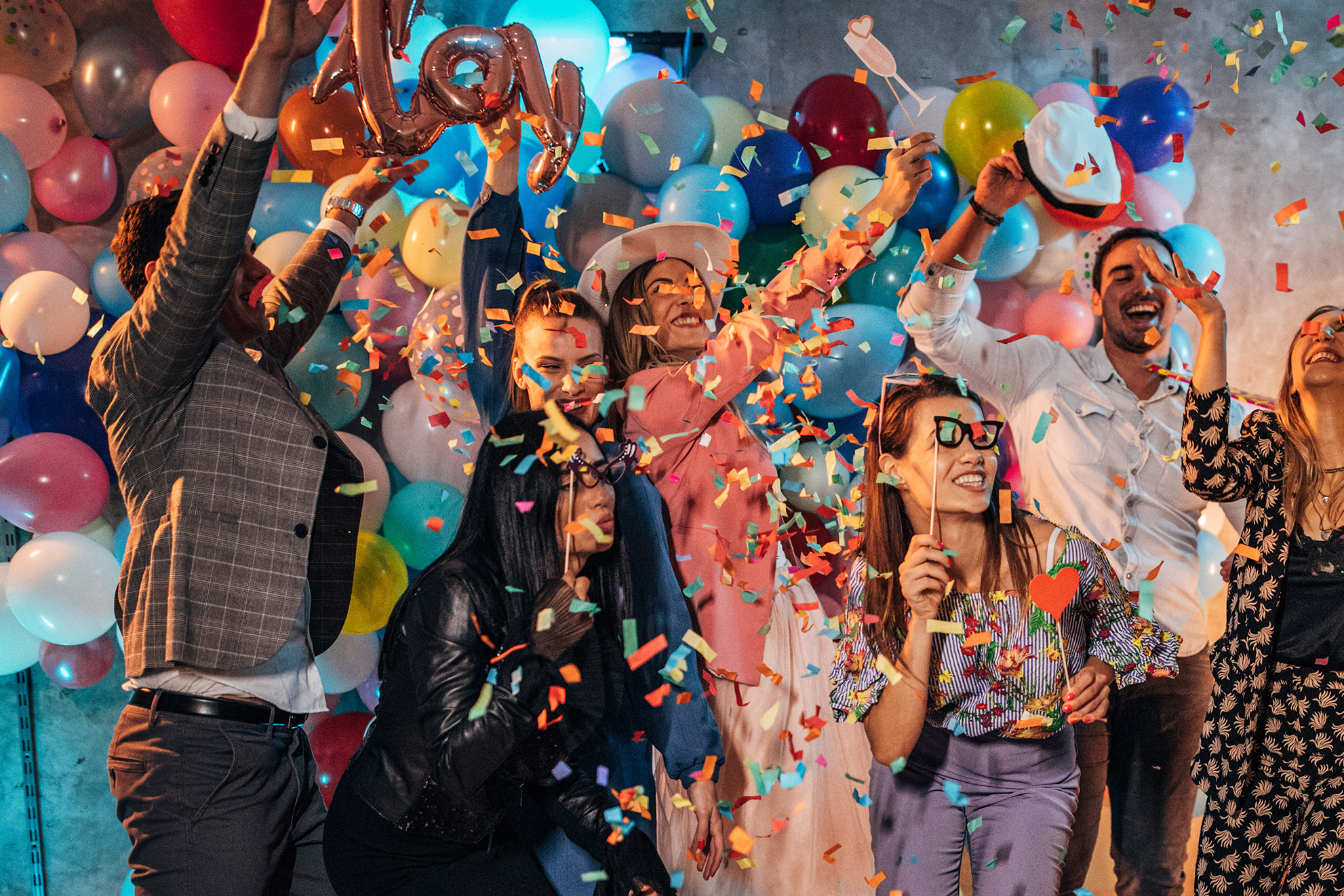 Group of young women and men having fun with balloons and photo booth at a party