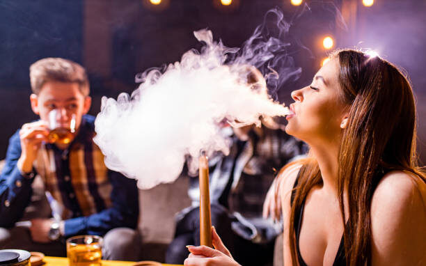 Friends party in hookah lounge smoking shisha night time.